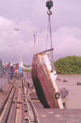 The tug Rickford L being lifted out of the Demerara River by a crane yesterday after it capsized (Photo by Jeanna Pearson)