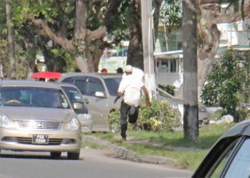 A very athletic constable Devin Singh evading members of the media on Brickdam yesterday after he was charged with the assault of detainee Colwyn Harding. 