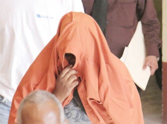 A covered Rosel Tilbury-Douglas returning to the holding cell at the Georgetown Magistrates’ Courts following her arraignment yesterday.  