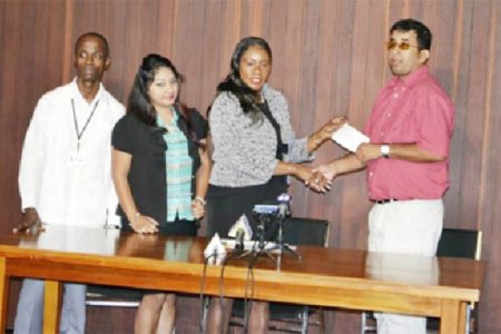 Minister of Human Services and Social Security, Jennifer Webster handing over the cheque to Ganesh Singh, while staff from the OLPF Secretariat look on. (GINA photo)