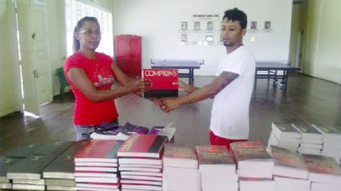 Senior PMCC cricketer Joshua Ramsammy presents a collection of books to the head librarian 
