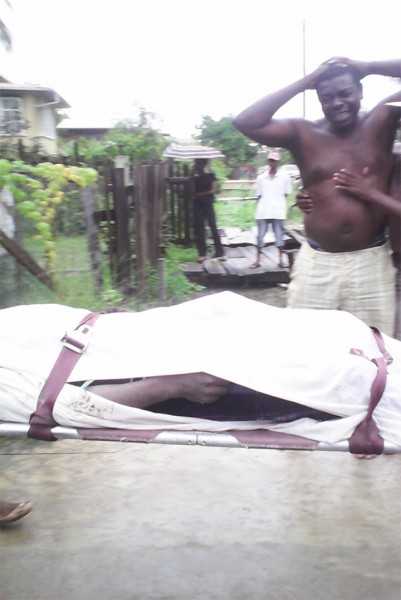 Gordon Sam grieving in the background as his son’s lifeless body is being carried to the vehicle waiting to transport him to the funeral parlour