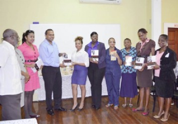 Minister of Culture, Youth and Sport Dr. Frank Anthony (seventh from right) handing over a copy of one of the Guyana Classics to a representative of the Parliament Library.  (GINA photo) 