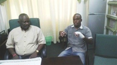 Junior Thornton displaying his injuries yesterday at APNU headquarters. At left is APNU MP Winston Felix