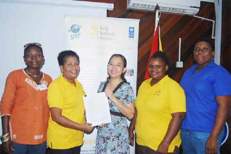 UNDP Resident Representative (ag), Ms. Chisa Mikami (centre) and Chairperson of the Kuru Kururu Farmers Crops and Livestock Association (KKFCLA), Denise Thomas (second from left) at the signing of the grant with the UNDP/GEF Small Grants Programme. Also in photograph are some of the executive members of KKFCLA.
