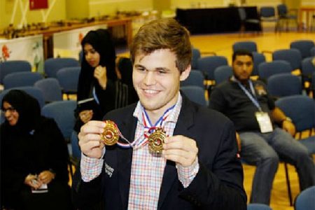 World chess champion Magnus Carlsen smiles as he displays the two gold medals certifying him the new World Rapid and Blitz Champion. The two championships were held in Dubai recently. Carlsen is now the undisputed triple crown champion of chess, having won the conventional title in November 2013 when he defeated Vishy Anand in India.