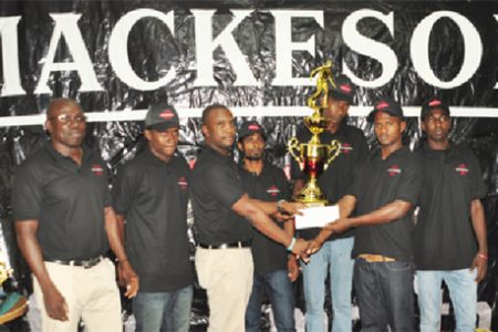Mackeson brand manager Jamal Douglas presents West Front Road skipper Hubert Pedro with the championship trophy while tournament coordinator Kevin Adonis (far left) and team members look on.
