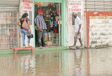 Customers using any dry ground available to edge their way into this King Street store yesterday during the flooding.