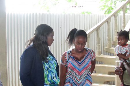 Minister of Human Services and Social Security, Jennifer Webster (left), speaking to the Bagot sisters’ sibling Malkia Bagot. (Ministry of Human Services photo)