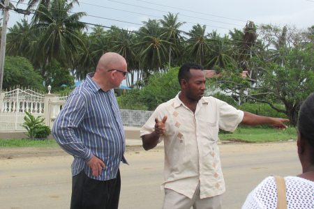 The dead sisters’ brother recounts the tragedy to the Deputy Permanent Secretary Patrick Findlay (left) at the scene.  (Ministry of Human Services photo)