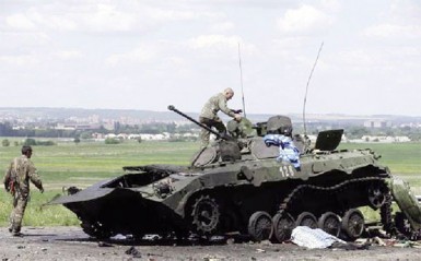 Ukrainian soldiers check a destroyed armoured vehicle at Slaviansk in eastern Ukraine yesterday. (Reuters/Maxim Zmeyev) 