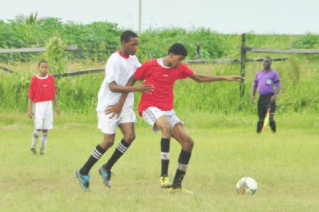 North Georgetown Secondary’s Nehemiah Gomes struggling to keep possession of the ball while being marked by a Guyana Industrial Training Centre player during their matchup.