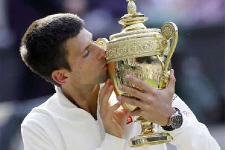 Novak Djokovic of Serbia kisses the winner’s trophy after defeating Roger Federer of Switzerland in their men’s singles final tennis match at the Wimbledon Tennis (Championships, in London yesterday. (REUTERS/Suzanne Plunkett)