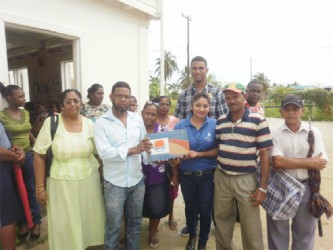 Supervisor of the OLPF Essequibo Branch Indrawattie Natram (fourth, right) hands over a laptop as residents and staff look on. 