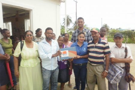 Supervisor of the OLPF Essequibo Branch Indrawattie Natram (fourth, right) hands over a laptop as residents and staff look on.
