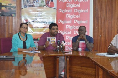 Minister of Tourism (ag) Irfaan Ali displays one of the festival passports at the ceremony as artiste Jumo Primo (right) and Event Coordinator of the Ministry Tameca Sukhdeo Singh (left) look on. (GINA photo) 
