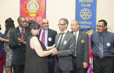 Demerara Rotary assistant district governor Marcel Gaskin congratulates incoming president Gillian Mohabeer as other Rotarians look on. 