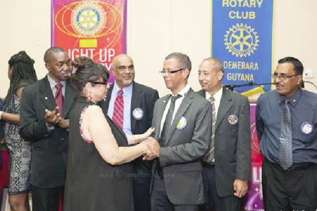 Demerara Rotary assistant district governor Marcel Gaskin congratulates incoming president Gillian Mohabeer as other Rotarians look on. 