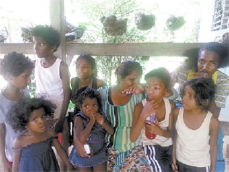 Natalie Baggan, 40, is comforted by eight of her 14 children hours after her 13-year-old son, Dayron Baker, was gunned down metres from their home at Cizan Trace, Diego Martin. 