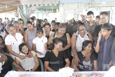 Relatives and mourers at the funeral service for 18-year-old Ashmini Harriram who was shot dead last Thursday shortly after her $15,000 cell phone was snatched from her hand. The service was held at her home following which she was cremated at Good Hope. Seated in this photo are her mother Khemwattie Samaroo and her two sisters.