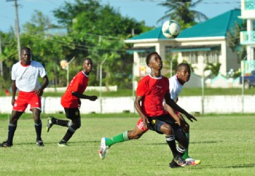 Second half goal scorer, Kareem Knights (red) of Chase Academy attempting to maintain possession of the ball while being challenged by a Morgan Learning Institute player during his side’s 3-0 win. 