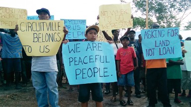 Scores of squatters greeted APNU MP Joseph Harmon with placards held high (Photo by Chevy Devonish) 