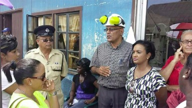 GPL CEO Bharat Dindyal (centre) speaking with residents at Bartica yesterday A Bartician with a placard Photo in Pictures/Mario/GPL/ IMG-20140725-WA003 