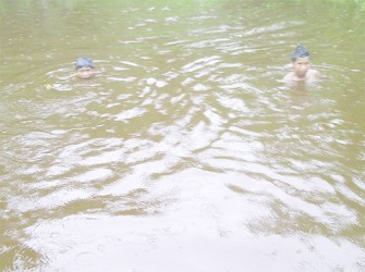 Two boys swimming in the small pond 