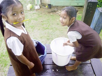 Two schoolchildren washing up for lunch at the hot meal dining house