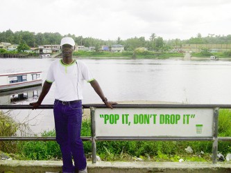 Robert Greene, a taxi driver and politically active community member standing next to an anti-littering sign on the river view tarmac overlooking the Demerara River