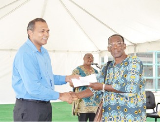Minister of Culture, Youth and Sport Dr. Frank Anthony (left) handing over a cheque to a member of one of the African Cultural groups (GINA photo) 