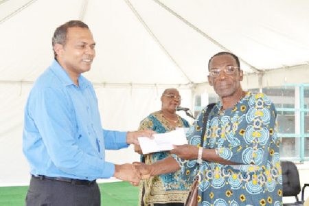 Minister of Culture, Youth and Sport Dr. Frank Anthony (left) handing over a cheque to a member of one of the African Cultural groups (GINA photo)