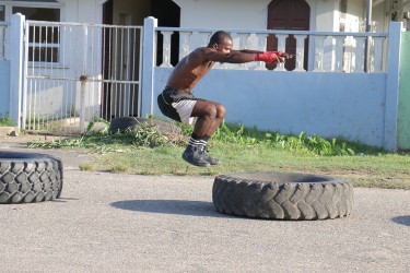 An amateur boxer doing squats on tyres along Independence Boulevard, Albouystown today.