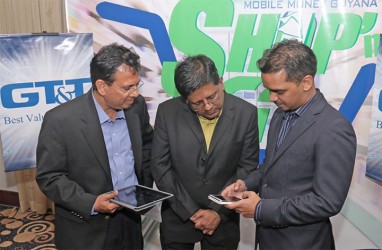 Eshwar Thakurdin, Managing Director of GT&T’s Mobile Money Guyana Inc, demonstrates the new Shop’n Go service for GT&T CEO RK Sharma (left) and Finance Minister Dr Ashni Singh. (Photo by Arian Browne)