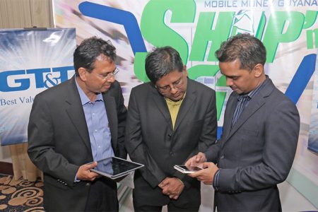 Eshwar Thakurdin, Managing Director of GT&T’s Mobile Money Guyana Inc, demonstrates the new Shop’n Go service for GT&T CEO RK Sharma (left) and Finance Minister Dr Ashni Singh. (Photo by Arian Browne)