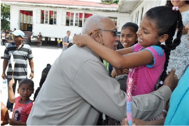 President Donald Ramotar being garlanded by a child of Wakapau, Region Two (GINA photo) 