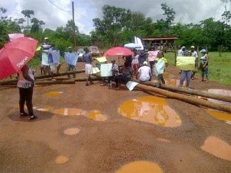 Residents sit on the poles they used to block the road 