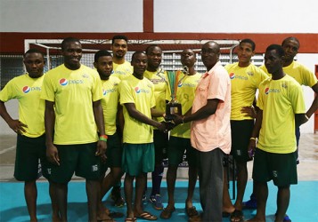 Captain Robert France of Pepsi Hikers collecting the division-A championship trophy from Guyana Hockey Board (GHB) Executive Ivor Thompson while other members of the team look on 