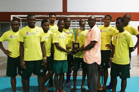 Captain Robert France of Pepsi Hikers collecting the division-A championship trophy from Guyana Hockey Board (GHB) Executive Ivor Thompson while other members of the team look on
