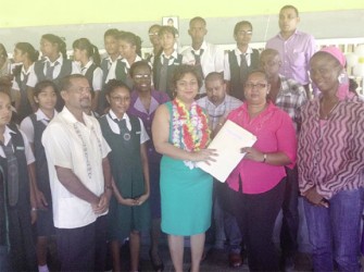 Minister of Education Priya Manickchand (centre) hands over a project outline for the extension of the West Demerara Secondary School to a staff member of the school