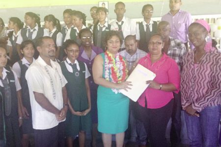 Minister of Education Priya Manickchand (centre) hands over a project outline for the extension of the West Demerara Secondary School to a staff member of the school
