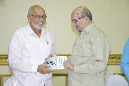 President Donald Ramotar (left) receives a copy of the book  ‘ Dancing between  the Raindrops’ from its author Dr Rudy Insanally. (GINA photo)