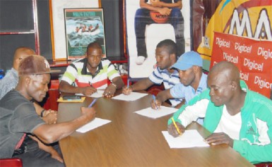 It’s official! Dexter Gonsalves (second from right) affixes his signature to his contract to make his ring date with Iwan Azore official. Other boxers signing their contracts yesterday were (from left) Derrick Richmond, (from right) Richard Williamson, Winston Pompey and Dexter Marques.  