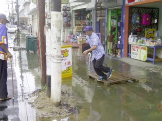A customer outside a Regent Street store jumping to dry land from a pallet surrounded by water