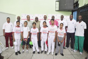 From third left Neil Kumar, Marcel Hutson, Brian Hackett and Colin Stuart standing with coaches and participants of the GCB/Scotiabank Kiddy Cricket Summer Camp.