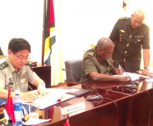 (From right) Major General Kong Li signs a US$4.8M Military Aid-Package with Chief of Staff Brigadier-General Mark Phillips yesterday at the opening ceremony of the Guyana-China Bilateral Staff Conference 2014 to strengthen the military in Guyana. 