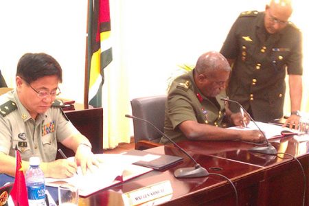 (From right) Major General Kong Li signs a US$4.8M Military Aid-Package with Chief of Staff Brigadier-General Mark Phillips yesterday at the opening ceremony of the Guyana-China Bilateral Staff Conference 2014 to strengthen the military in Guyana. 