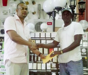General Manager of S&L Electrical Agency Daniel Pemberton (left) handing over the sponsorship cheque to Netrockers FC coach Eyon Wills 