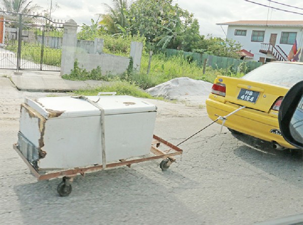 The recommended method of transporting  a freezer: A freezer being towed by a taxi along the Public Road at Land of Canaan, EBD, yesterday (Photo by Arian Browne) 