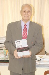 Yesu Persaud with the first volume of his autobiography at the book launch earlier this year (Stabroek News file photo)